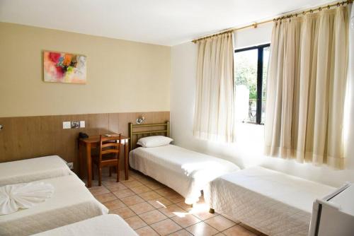 a hotel room with two beds and a desk at Santa Maria Hotel in Cascavel