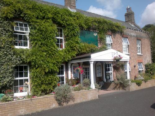 an ivy covered house with a whiteconservatory at Andel Lodge & Restaurant in King's Lynn