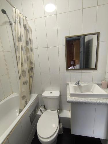 a white bathroom with a toilet and a sink at Hostal Rancel in Angol