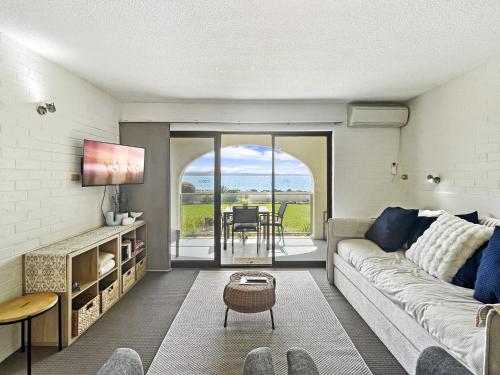 a living room with a couch and a table at Beachside Apartment Overlooking Caseys Beach in Batehaven