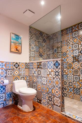 a bathroom with a toilet and a mosaic wall at Hotel y Restaurante Buganvilias in Las Aradas