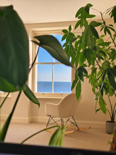a room with a chair in front of a window at Ocean Whisper - 2 Bedroom Sea Front Apartment in Folkestone