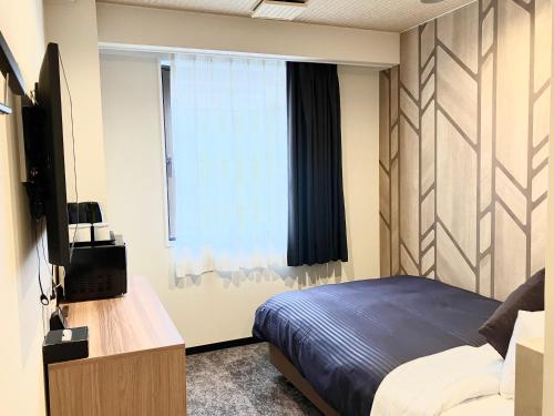 a bedroom with a bed and a television and a window at HOTEL LiVEMAX BUDGET Chofu-Ekimae in Chofu