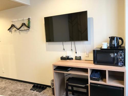 a room with a desk with a tv and a microwave at HOTEL LiVEMAX BUDGET Chofu-Ekimae in Chofu