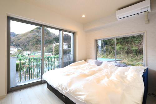a bedroom with a bed and a large window at ゲストハウス&café chiuwo in Kawazu