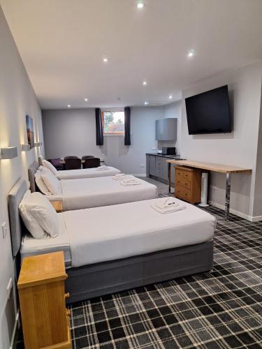a hotel room with three beds and a flat screen tv at Crown Hotel & Bar in Inverness