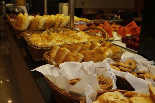 a buffet filled with baskets of bread and pastries at Hotel Pouso Real in Rio de Janeiro