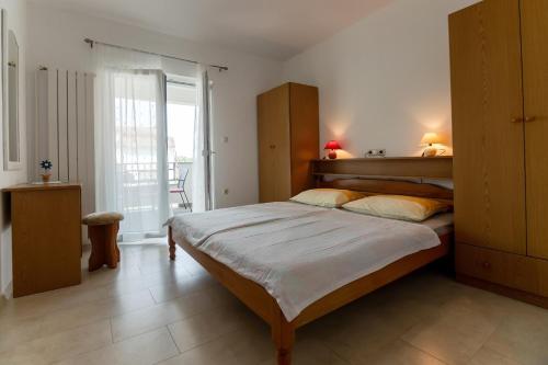 a bedroom with a large bed and a balcony at Apartments and rooms by the sea Palit, Rab - 5044 in Rab