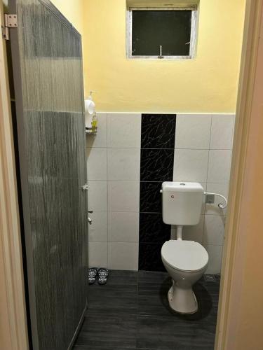 a bathroom with a white toilet and a window at Homestay D'Kampong in Teluk Intan