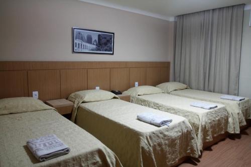 a hotel room with three beds with towels on them at Hotel Pouso Real in Rio de Janeiro
