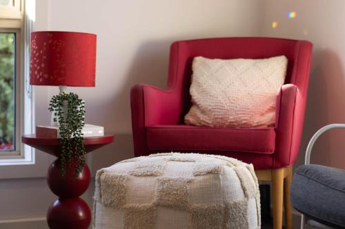 a living room with a red chair with a pillow at Canvas & Comfort Peaceful Ballarat Base in Wendouree