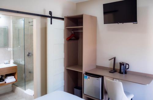 a bathroom with a bed and a shower and a television at TStays Smart Hotel Courtyard, Gated Modern Stay in Port-of-Spain