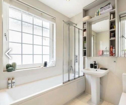 a bathroom with a tub and a sink and a window at Layla Grove in Grove Park