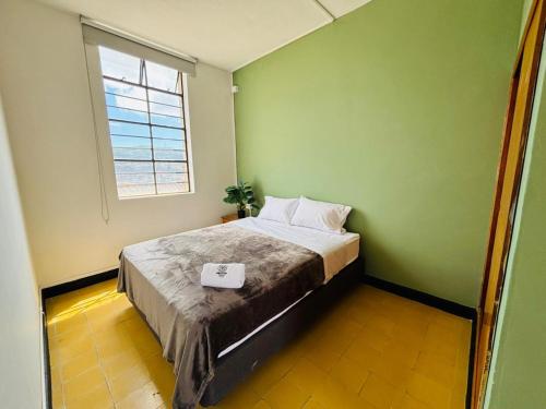 ein kleines Schlafzimmer mit einem Bett und einem Fenster in der Unterkunft Hostal Capullode Seda in Zapatoca