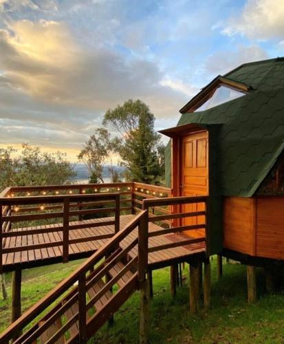 a wooden cabin with a green roof and benches at Eclipse de luna Guatavita in Guatavita