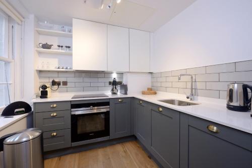 a kitchen with gray and white cabinets and a sink at Destiny Scotland - Distillers House in Edinburgh