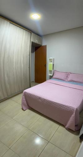 a bedroom with a large bed with pink sheets at Casa Lagoa Maior Espaçosa e confortável! in Três Lagoas