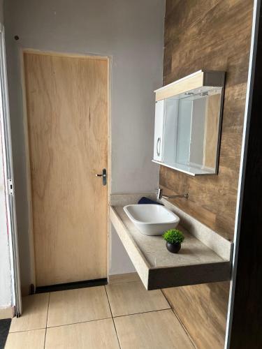 a bathroom with a sink and a wooden door at Casa Lagoa Maior Espaçosa e confortável! in Três Lagoas