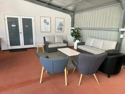 a living room with couches and a table and chairs at Mudgee Vineyard Motor Inn in Mudgee
