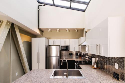 a kitchen with white cabinets and a stainless steel refrigerator at Downtown Luxury 2BR Penthouse Loft - Sleeps 6-8 in Milwaukee