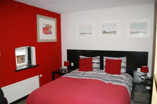 a red bedroom with a bed with two red pillows at Bed&Breakfast Maasland in Maasland