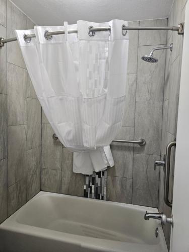 a bath tub with a shower curtain in a bathroom at Super 8 by Wyndham Hobbs in Hobbs