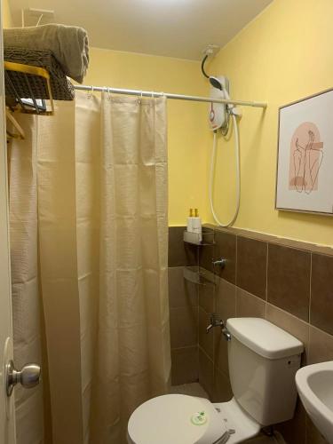 a bathroom with a shower curtain and a toilet at 1 Bedroom Arezzo Condotel in Davao City
