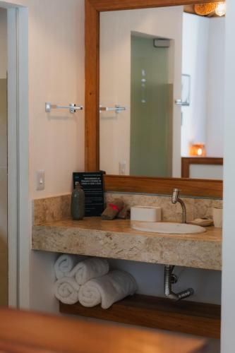 a bathroom with a sink and a mirror and towels at LAUS Bangalôs Experience - Piscina Privativa - Praia de Algodões - Península de Maraú - Bahia in Praia dos Algodões