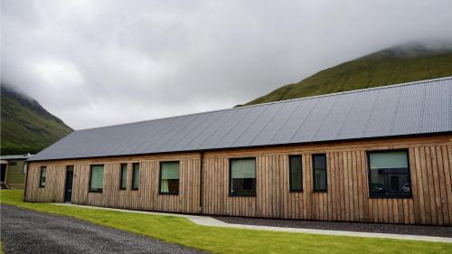 a building with a metal roof with mountains in the background at Auch - Trail Cabins in Bridge of Orchy