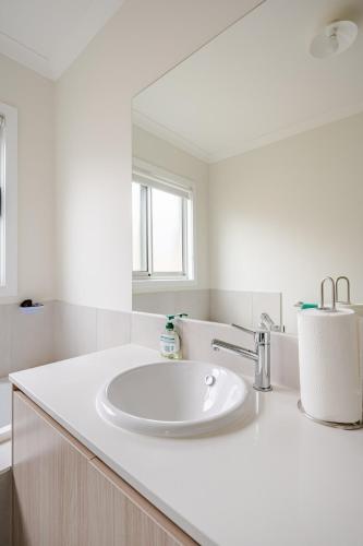 a white bathroom with a sink and a mirror at Neat and tidy house in Cranbourne