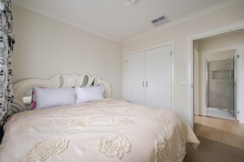 a white bedroom with a large white bed with a window at Neat and tidy house in Cranbourne