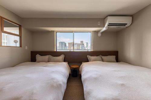 two beds in a room with a window at The Residence Sapporo - すすきの駅から徒歩6分 - in Sapporo