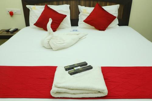 a bed with white towels and red pillows at Hotel Priso in Kālapettai