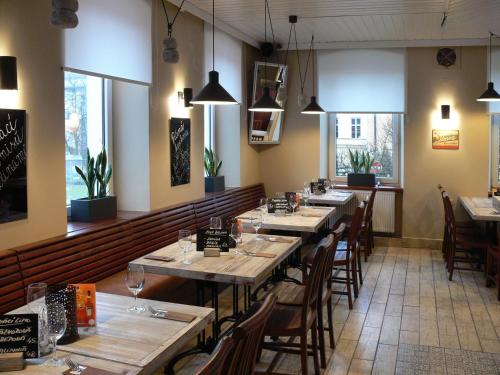 a restaurant with long tables and chairs and windows at Hotel Na Baste in Jablonec nad Nisou