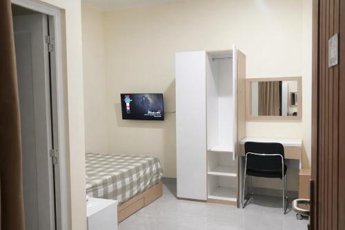 a bedroom with a bed and a desk and a television at Diponegoro House Solo Baru in Solo
