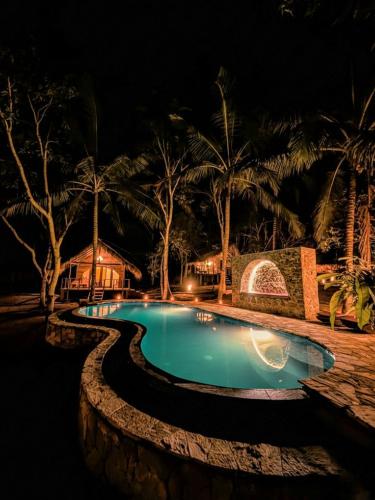 a swimming pool at night with palm trees at Gaga Bees Udawalawe in Udawalawe