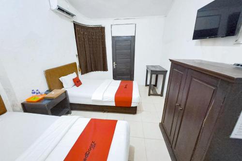 a hotel room with two beds and a television at RedDoorz at Lumungga Residence Lampung in Lampung