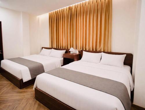 a hotel room with two beds and a window at Vũ Ngọc Hotel Núi Sam in Chau Doc