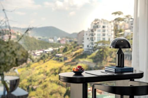 a table with a lamp and a bowl of fruit on it at CICILIA Rouge Dalat in Da Lat