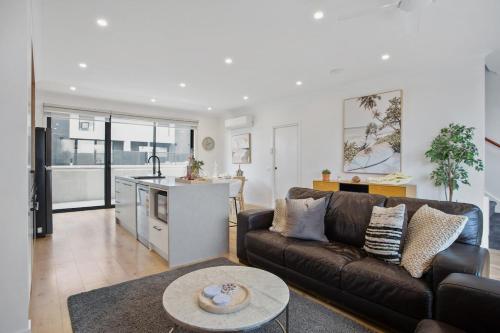 a living room with a brown couch and a kitchen at Williamstown Townhouse in Williamstown