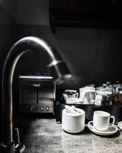 a kitchen counter with cups and saucers next to a toaster at IGN Residence Colombo in Colombo