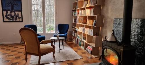 a living room with two chairs and a fireplace at Au Pré du Chêne in Le Faouët