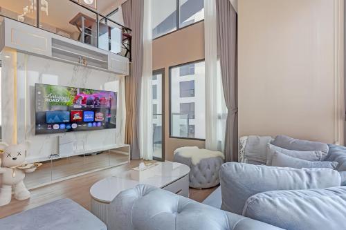 a living room with blue furniture and a tv at Cassia Residence Rama 9 Bangkok in Bangkok