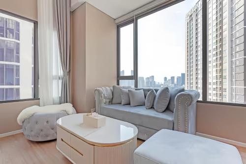 a living room with a blue couch and large windows at Cassia Residence Rama 9 Bangkok in Bangkok