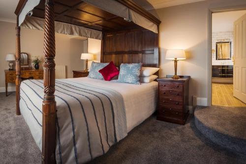 a bedroom with a canopy bed with blue and red pillows at Royal Seven Stars Hotel in Totnes