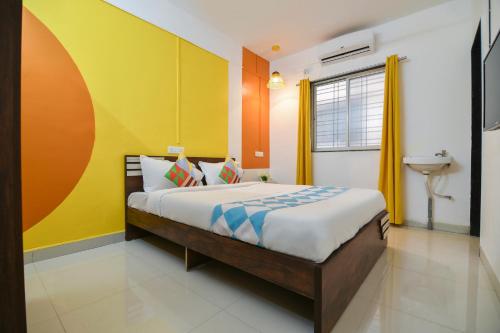a bedroom with a bed and a yellow and orange wall at HOTEL O THE G STAY in Chinchwad