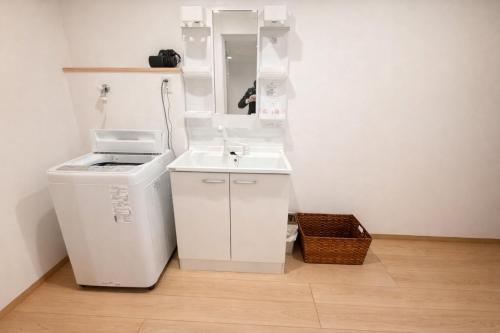 a white bathroom with a sink and a mirror at 舒爽旅馆 in Fuefuki