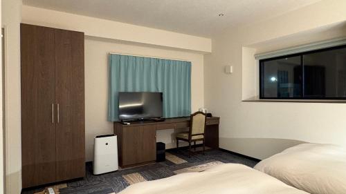 a hotel room with a bed and a desk with a television at Hotel Forest Echo 森のこだま