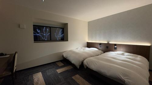two beds in a room with a window at Hotel Forest Echo 森のこだま