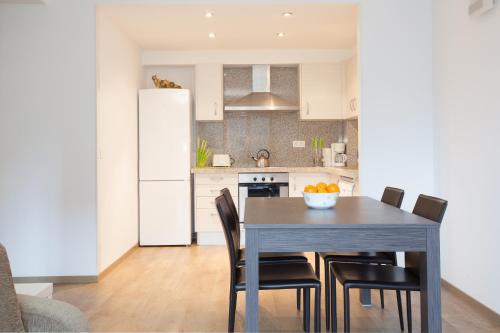 a kitchen with a table and chairs and a white refrigerator at Apartaments Les Terrasses del Tarter in El Tarter